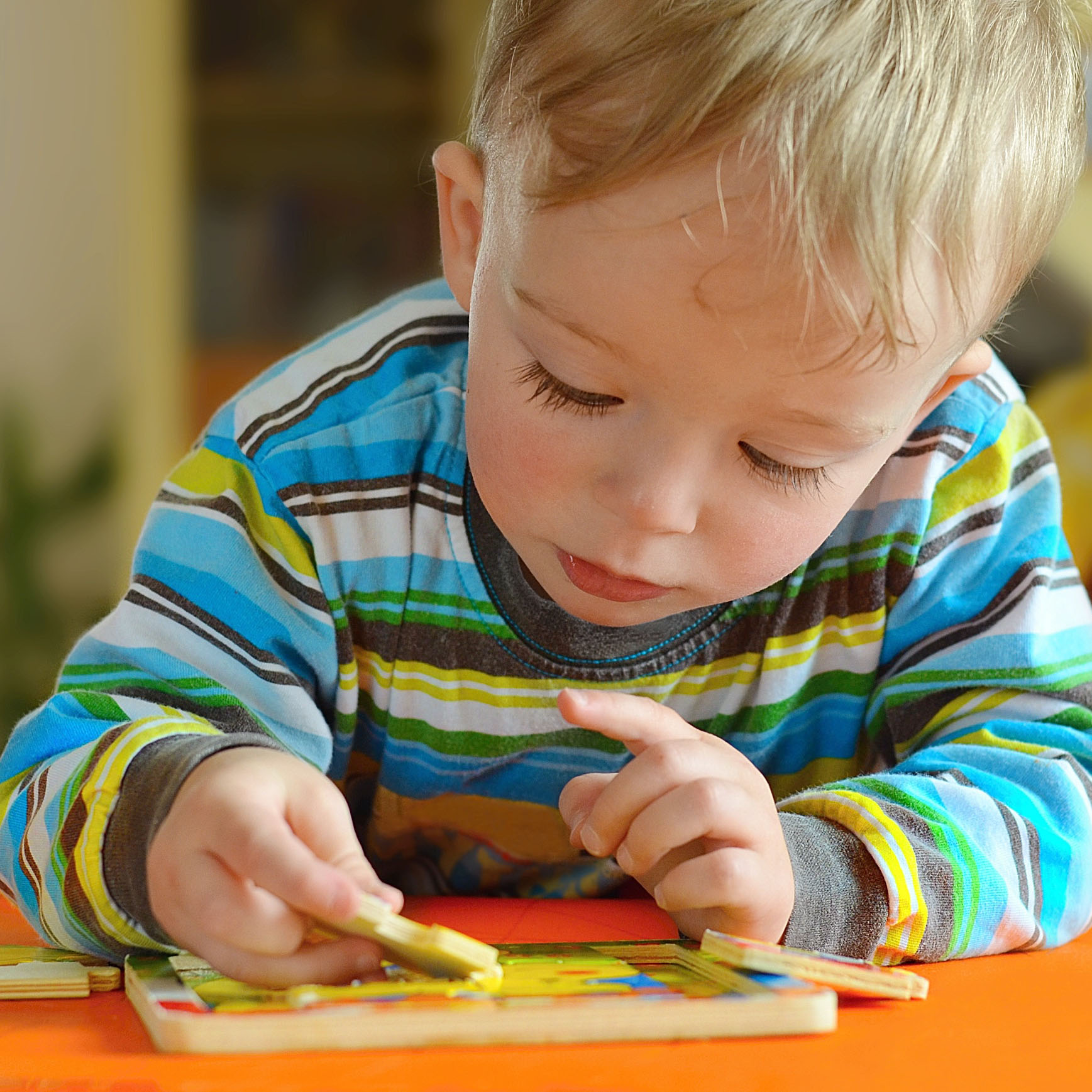 A toddler plays with a wooden puzzle.