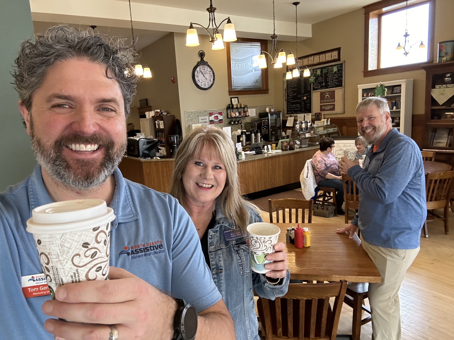 Tom Gerhardt, Beth Olson, and Mike Chaussee pose for a photo holding coffees from the Maddock Opera House.