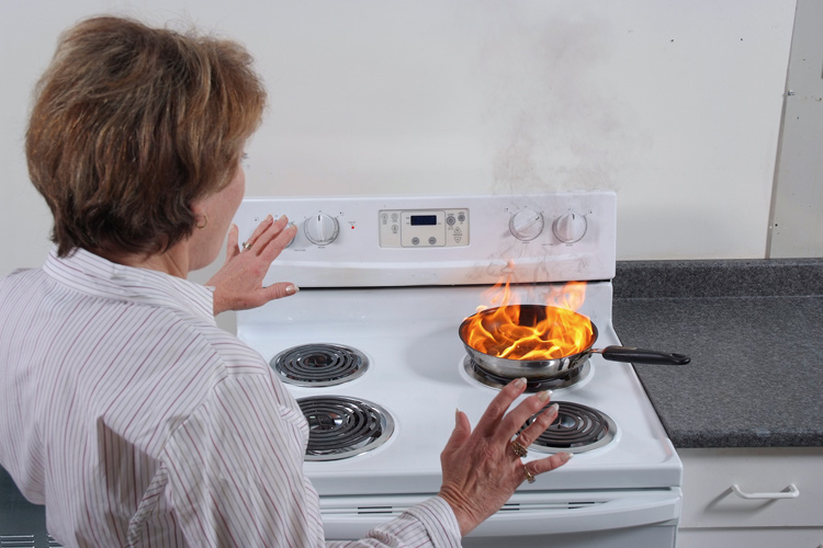 Woman next to stove on fire.