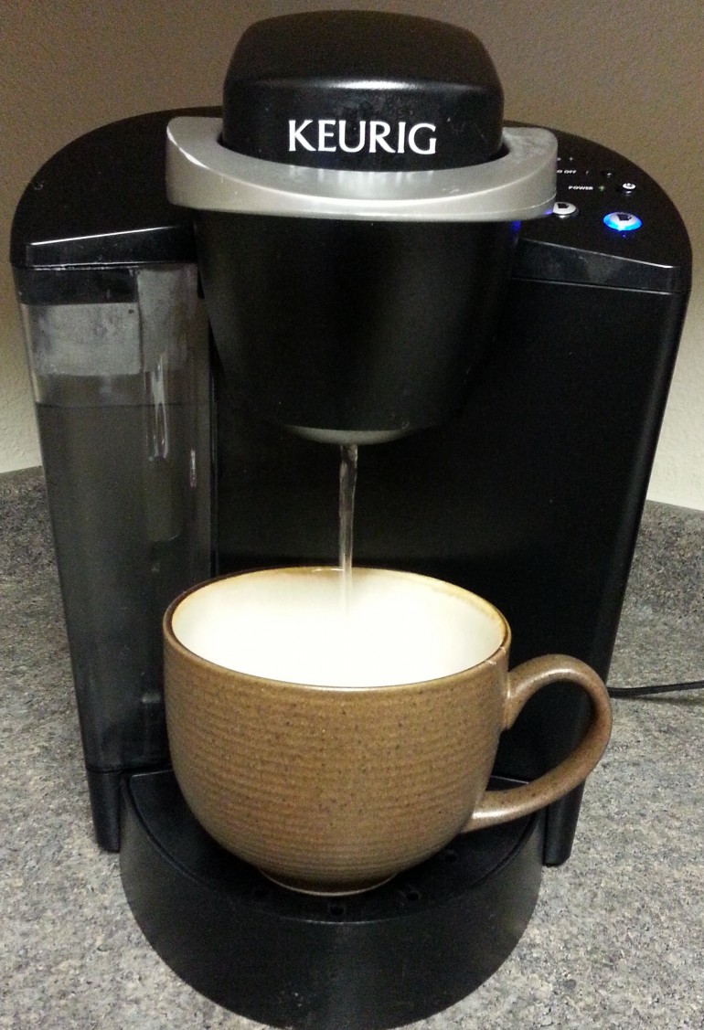 Keurig coffee maker running hot water into a coffee cup with InstaMorph pellets in it.