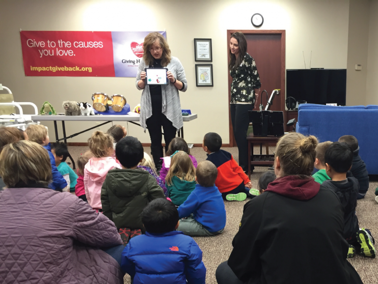 Assistive Technology Consultants Jeannie Krull and Trish Floyd are demonstrating various pieces of assistive technology to a group of preschoolers.