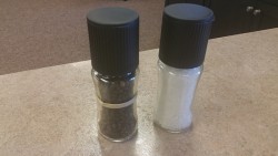 In this picture are two identical salt ’n’ pepper shakers with a rubber band around one of them.