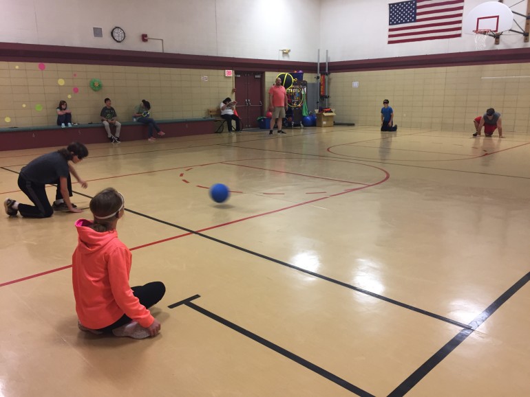 Teenagers playing Goalball while others look on.