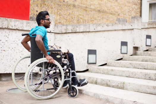 man in a wheelchair waiting at the bottom of steps