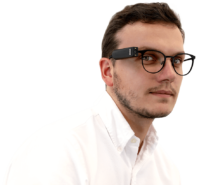 Photo of man wearing glasses with small black OrCam connected to eyeglass frame