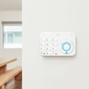 Small white rectangular security system device with keypad mounted on a wall