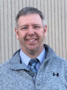 headshot photo of a man wearing a gray sweater