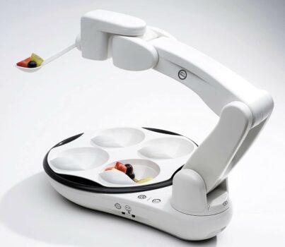 OBI self-feeding device with white arm and food in compartments and spoon.