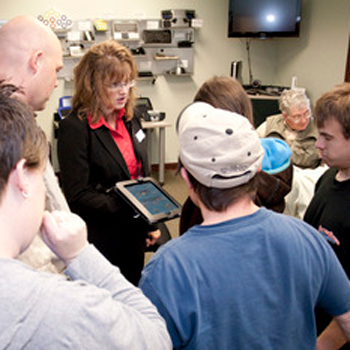 Picture of AT Consultant showing a device to a group of people.