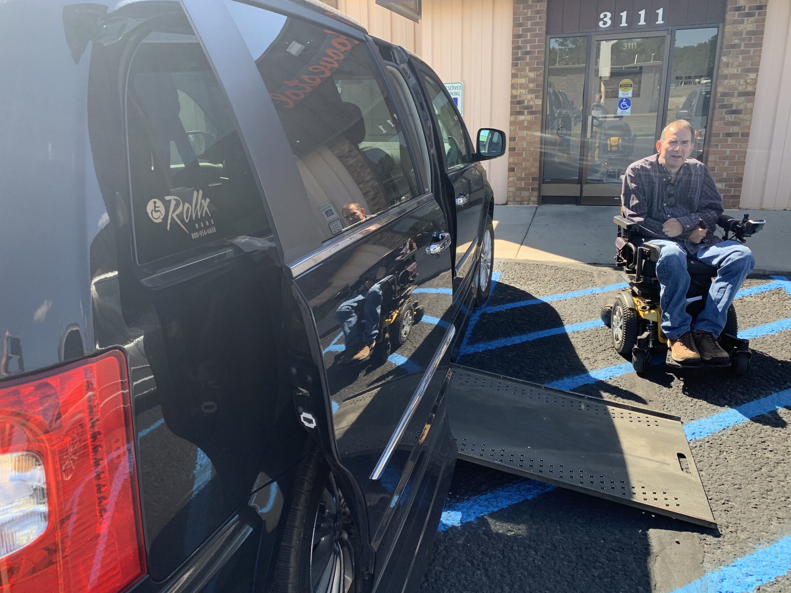 Royce Schultze outside of his accessible van. Sun is out. Ramp is extended and he is approaching the ramp.