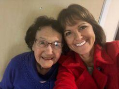 smiling elderly mother in blue sweater with smiling daughter in red coat