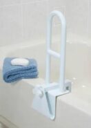 Tub grab bar attached to rim of bathtub with a blue towel with a bar of soap laying on the rim of the tub.