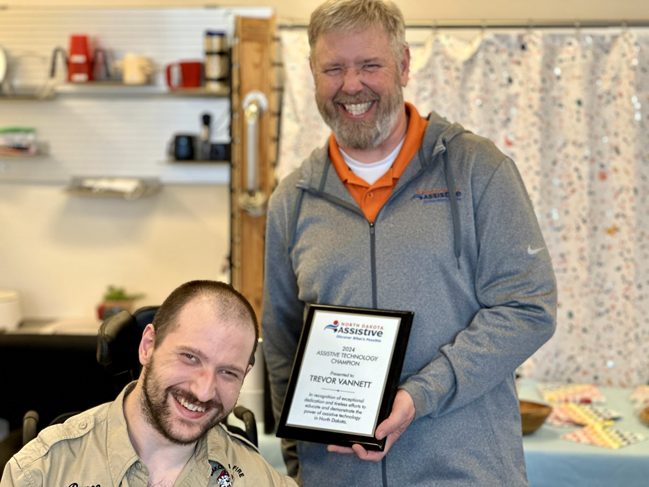Mike Chaussee presents Trevor Vannett with a plaque honoring him as a 2024 Assistive Technology Champion.